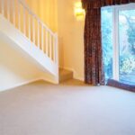 Empty living room with red patterned curtains and staircase