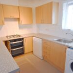 Kitchen with white goods and light brown cupboards