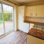 Kitchen with brown floors and sliding glass door leading to garden