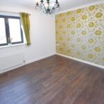 Bedroom with green curtains and patterned wallpaper feature wall