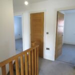 Upstairs hallway with grey carpets and wooden doors in rental house