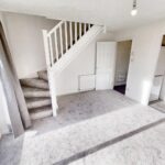 Unfurnished living room with grey carpet on floor and stairs