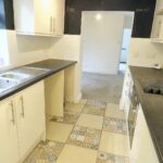 Black and cream coloured kitchen with detailed floor tiles in rental property