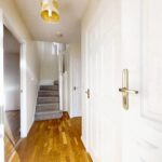 Downstairs hallway with wooden floors and carpeted stairs in Milton Keynes rental property