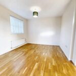 Unfurnished living room with green lampshade and wooden floors in house to rent in Milton Keynes