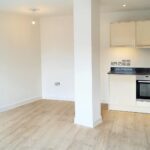 Kitchen and lounge with large white pillar in flat to rent near Milton Keynes