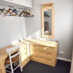 Third bedroom with wooden furniture and area to hang clothes in MK rental property