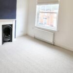 Unfurnished lounge with white carpet and dark blue feature wall in 2 bedroom house to rent near Milton Keynes