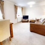 Furnished living room with leather sofa, TV and table with four chairs in flat to rent in Milton Keynes