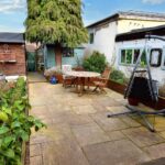 Well-maintained back garden with wooden furniture and hanging chair in Milton Keynes rental property